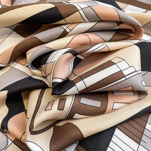 Macro detail of silk scarf showing abstract geometric patterns and smooth satin texture
