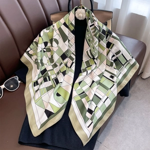 Geometric floral silk scarf with green and beige pattern draped on a black top