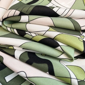 Macro shot of geometric floral twill scarf showing silk texture and forest green details