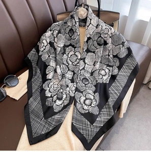 Detail of floral silk square scarf with camellia print draped on a leather couch
