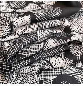 Detailed macro view of black and white floral twill fabric texture with soft sheen