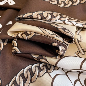 Vue macro d'un foulard en soie à motif équestre montrant la texture du tissu sergé