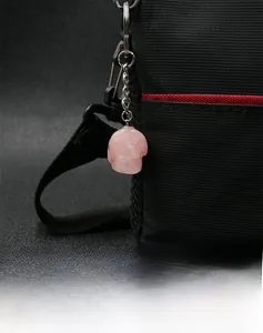 Macro shot of rose quartz skull keychain attached to a black bag showing detailed carving