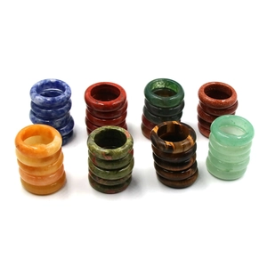 Stack of natural gemstone rings including lapis lazuli and tiger eye on white background