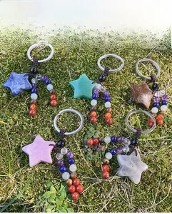 Detail of five star-shaped natural crystal keychains with colorful beads on moss