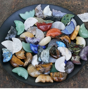 Detailed pile of assorted hand-carved natural crystal moon face stones in a black tray