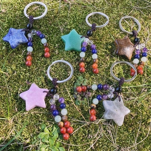 Natural gemstone star keychains with chakra beads on mossy ground, healing style
