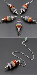 Detailed view of Seven Chakra stone pendulum with polished metal tip and layered crystals