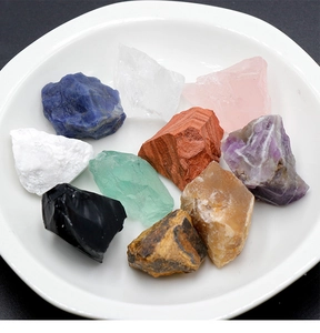Variété de pierres précieuses brutes naturelles comme l'améthyste et le quartz sur un plat blanc