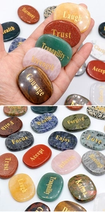 Detailed view of hand-held natural crystal stones with engraved golden inspirational words