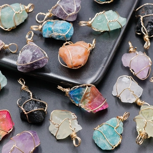 Handcrafted natural crystal pendants with gold wire wrap on a black textured background