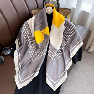 Elegant 90cm square silk scarf with yellow and grey geometric prints draped on clothing