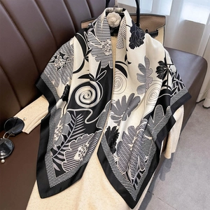 Elegant black and white floral silk scarf displayed on a leather sofa for a chic look