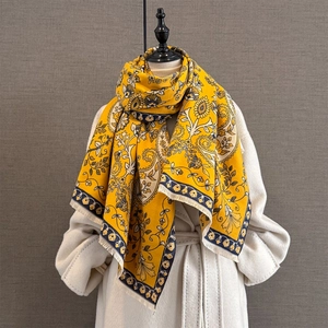 Châle jacquard cachemire jaune avec franges porté sur un long manteau en laine blanc