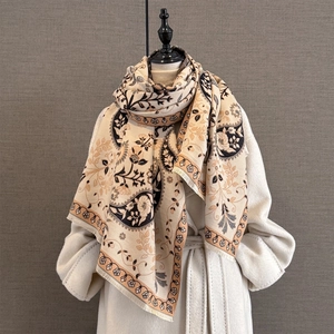 Détail d'une écharpe beige aspect cachemire à motif paisley et franges sur manteau