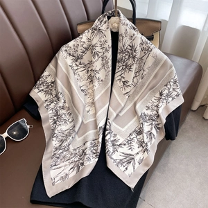 Elegant bamboo leaf print silk scarf in beige and grey draped on a leather background