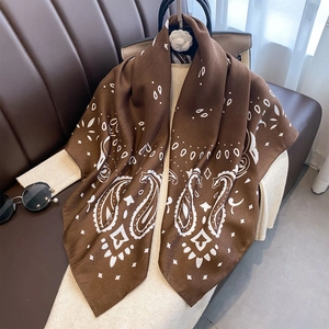 Braunes Seidentuch mit weißem Paisleymuster, drapiert über einem beigen Strickpullover