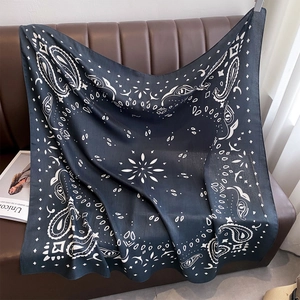 Detailaufnahme eines dunkelblauen Paisley-Quadrattuchs auf braunem Lederhintergrund