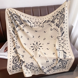 Detailaufnahme eines beigen Paisley-Halstuchs drapiert auf einem Ledersofa