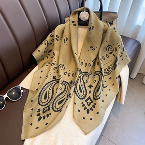 Detail eines olivgrünen Seidenschals mit Paisley-Muster und feinen Nähten am Rand