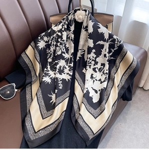 Detail of vintage floral silk scarf draped on a leather handbag with a camellia brooch