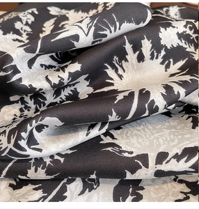Macro detail of the high-density twill weave and black floral print on a satin scarf