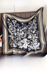 Close-up of vintage thistle pattern silk scarf in black and beige on leather background