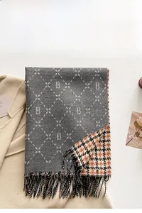 Detail of grey cashmere-like scarf with letter B jacquard and houndstooth pattern fringe