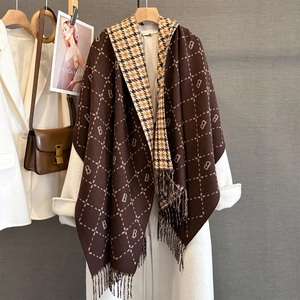 Detail of the letter B pattern and tassel fringe on a brown checkered cashmere scarf