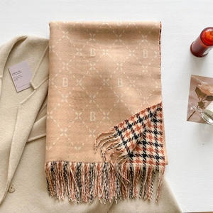 Detail of beige letter B patterned scarf with houndstooth texture and tassels