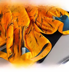 Close-up of the precise stitching and fine edge craft on a yellow silk-like printed scarf
