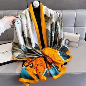 Elegant silk scarf with landscape print and orange border shown in a draped view