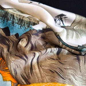 Elegant silk scarf with landscape print in earthy and blue tones, draped with soft texture