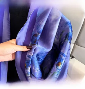 Detailed view of the fine stitched edges on a silky satin scarf with blue and purple prints