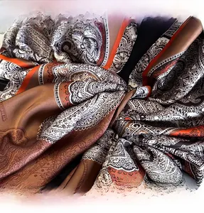 Detailed close-up of paisley silk scarf edge featuring dense overlock stitching and soft folds