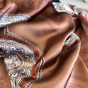 Elegant paisley print silk scarf in warm brown and beige with smooth satin finish