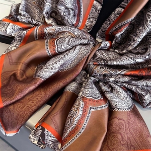 Retro paisley print silk scarf in warm coffee and orange tones with elegant satin finish