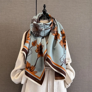 Detailed texture of blue-gray scarf showing lotus print and soft fringe trim