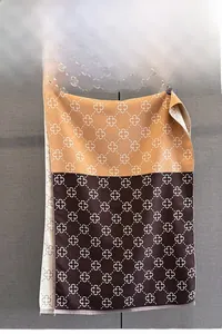 Detail of two-tone jacquard scarf featuring orange clover patterns and fringe edges