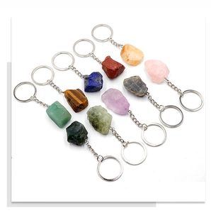 Set of ten assorted raw natural gemstone keychains with silver metal rings on white background