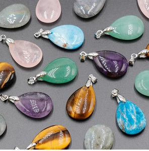 Detailed flat lay of teardrop natural gemstone pendants with silver clasps on grey surface