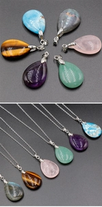 Detailed close-up of colorful teardrop gemstone pendants on a black textured surface
