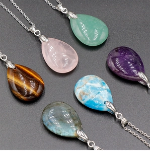 Detailed view of teardrop gemstone pendants including amethyst and tiger eye on silver chains