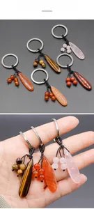 Macro detail of tear-drop shaped natural crystal keychains held in hand for size