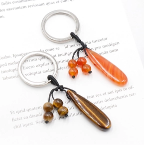 Detailed view of teardrop Tiger Eye and Red Agate stones on braided rope keychains