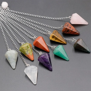 Assorted hexagonal crystal point dowsing pendulums with silver chains on grey background