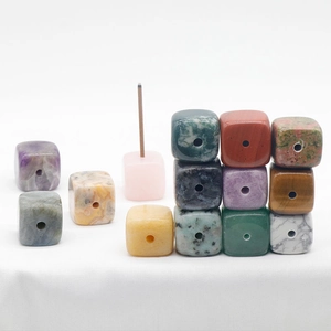Natural crystal agate cube incense holders in various colors on a white fabric base