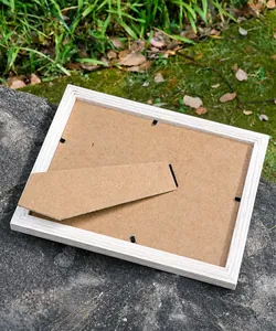 Back view of natural wooden frame with adjustable stand and black metal clips on a rock