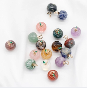 Macro detail of assorted apple-shaped crystal pendants with gold leaf leaf metal hooks