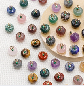 Macro shot of assorted gemstone apple pendants with gold metal leaves and green enamel